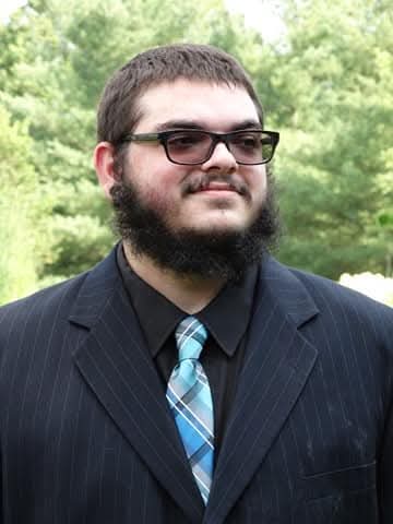 A photo of Kevin White, he is wearing a suit with a tie, and glasses with short hair, and a beard. he is the owner and operator of Computer Repair USA.