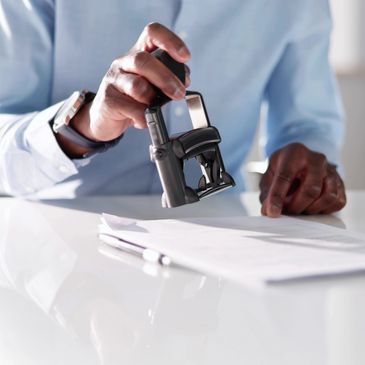 A photo of a person stamping a piece of paper or document with a notary stamp.