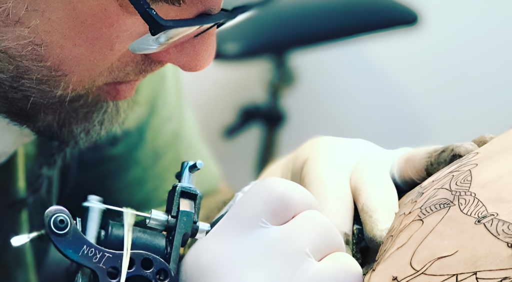 A Tattoo Artist Tattooing A Hourglass.